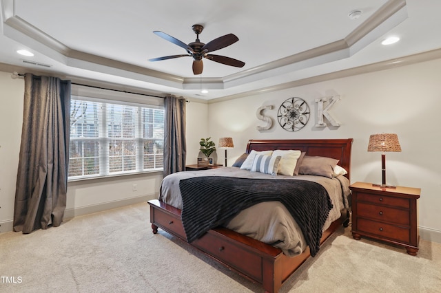 bedroom with ornamental molding, light carpet, ceiling fan, and a tray ceiling