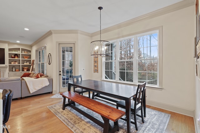 dining space featuring an inviting chandelier, plenty of natural light, ornamental molding, and light wood-type flooring