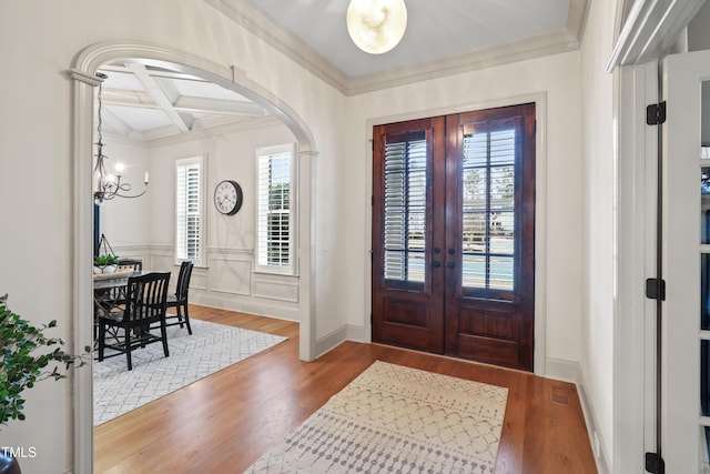 entryway with a chandelier, coffered ceiling, wood-type flooring, french doors, and beamed ceiling