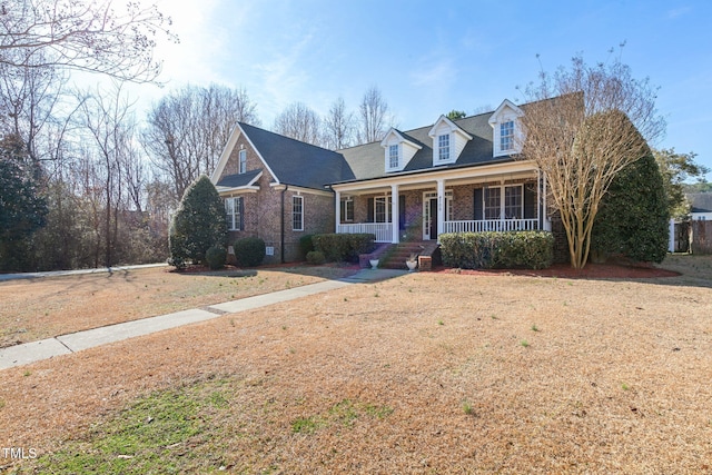 new england style home featuring a front lawn and covered porch