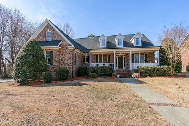 cape cod-style house featuring covered porch and a front yard