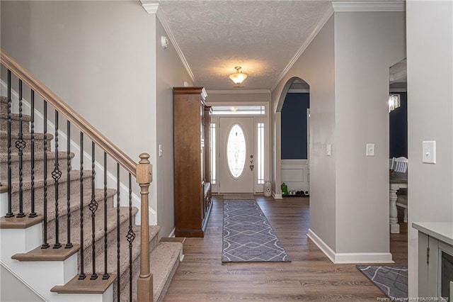 foyer entrance with ornamental molding, dark hardwood / wood-style floors, and a textured ceiling