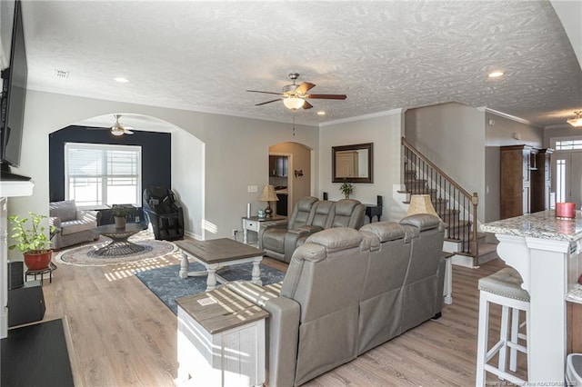 living room with ceiling fan, ornamental molding, and light wood-type flooring