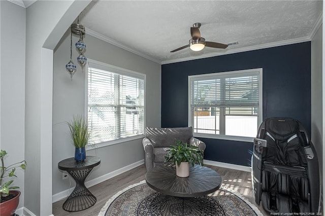 living area with ornamental molding, hardwood / wood-style floors, a textured ceiling, and ceiling fan