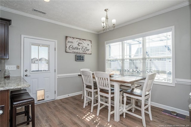 dining area with crown molding, a textured ceiling, a notable chandelier, and dark hardwood / wood-style flooring