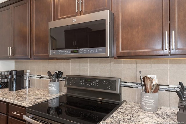 kitchen with stainless steel appliances, light stone countertops, and decorative backsplash