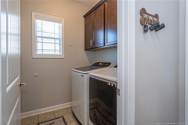 laundry area featuring light tile patterned flooring, cabinets, and washing machine and dryer