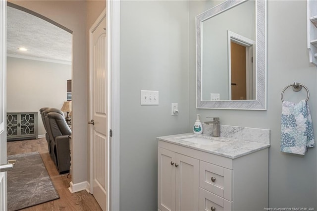 bathroom with vanity, hardwood / wood-style floors, crown molding, and a textured ceiling