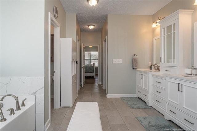 bathroom with vanity, a tub to relax in, tile patterned floors, and a textured ceiling