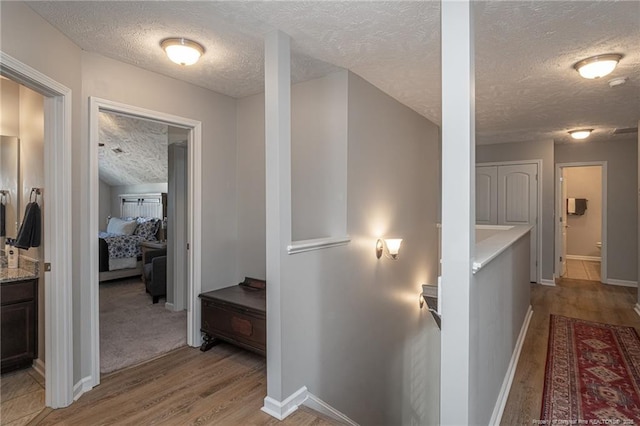 corridor featuring light hardwood / wood-style flooring and a textured ceiling