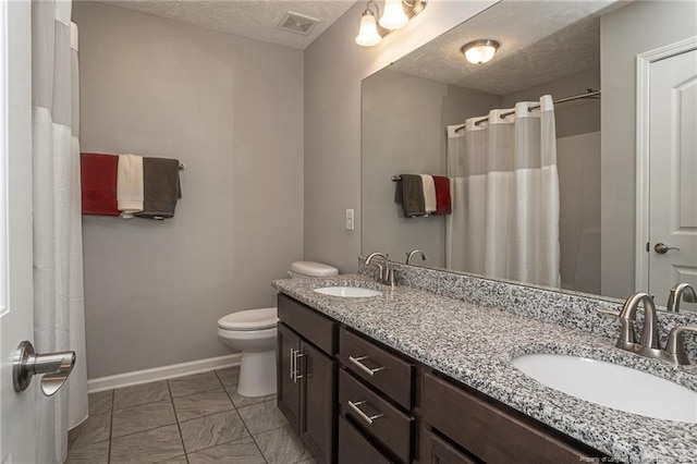 bathroom featuring vanity, a textured ceiling, and toilet