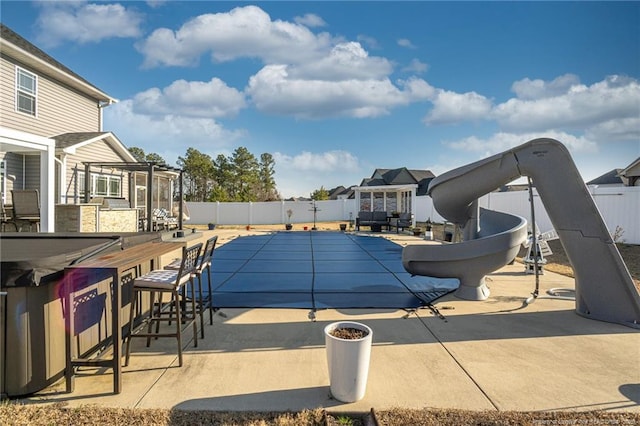 view of swimming pool featuring a bar, a patio area, and a water slide