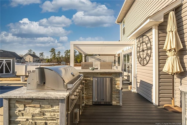 wooden deck featuring a grill, a pergola, exterior bar, and an outdoor kitchen