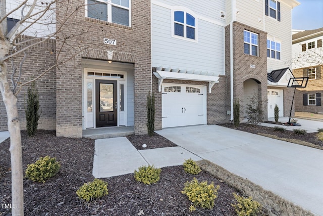 view of front of house featuring a garage, concrete driveway, and brick siding