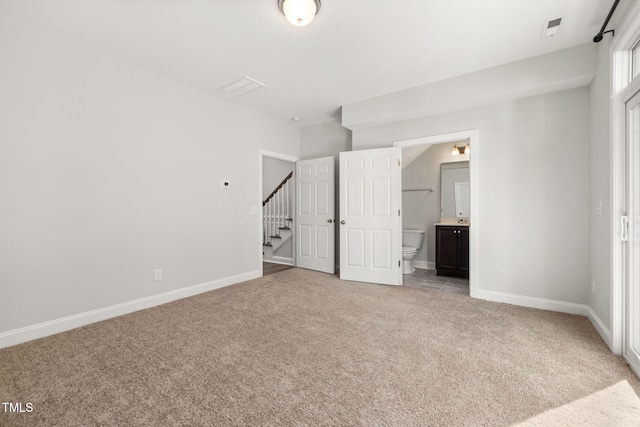 interior space featuring light carpet, ensuite bath, and baseboards