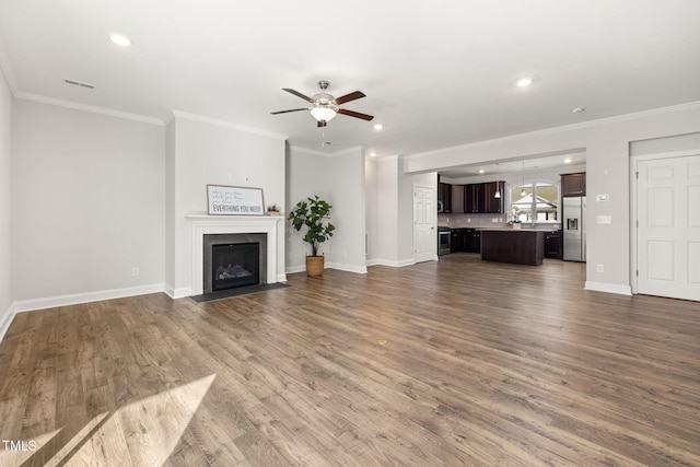 unfurnished living room featuring wood finished floors, ornamental molding, a fireplace with flush hearth, and visible vents