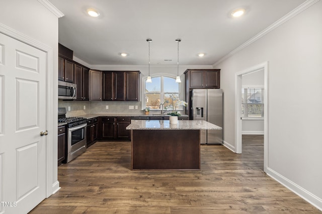 kitchen with dark brown cabinetry, a kitchen island, stainless steel appliances, and crown molding