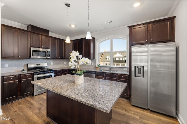 kitchen featuring dark brown cabinetry, appliances with stainless steel finishes, a sink, and ornamental molding