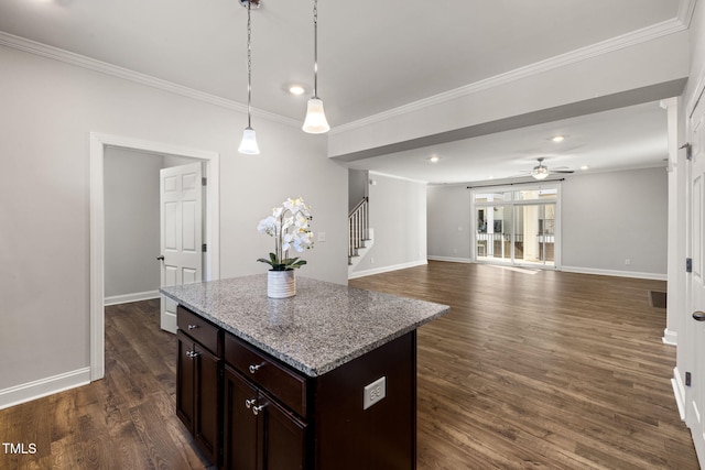 kitchen with ornamental molding, dark wood finished floors, light stone counters, and a center island