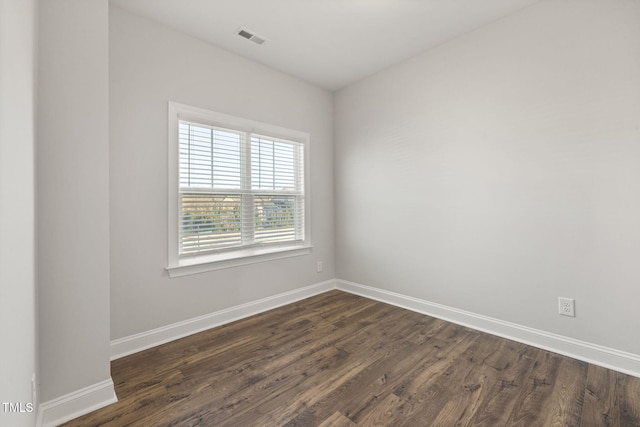 unfurnished room with dark wood-style floors, visible vents, and baseboards