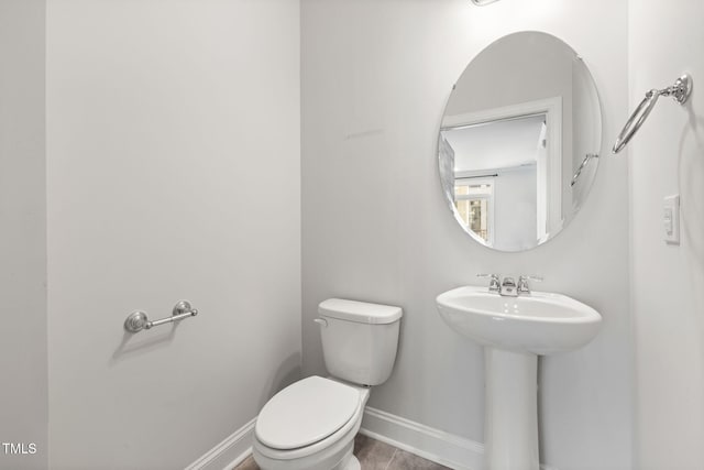 bathroom featuring toilet, baseboards, and a sink