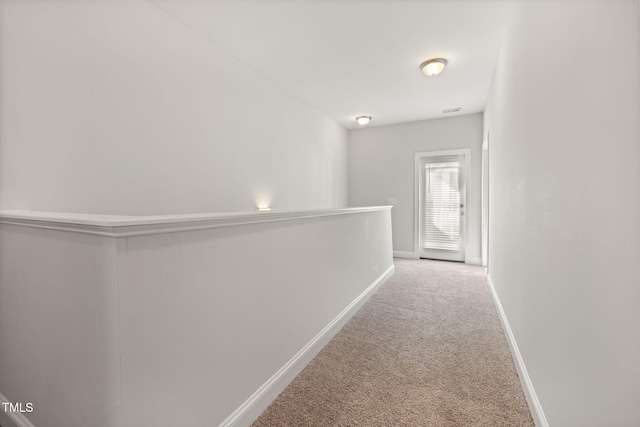 hall featuring baseboards and carpet flooring