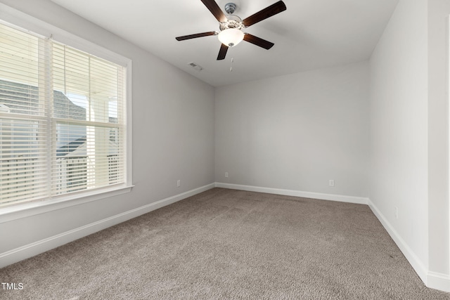 carpeted empty room with a ceiling fan, visible vents, and baseboards