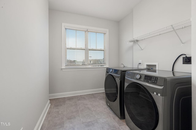 clothes washing area with washing machine and dryer, laundry area, baseboards, and light tile patterned floors