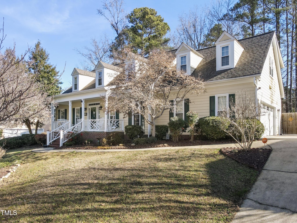 cape cod home featuring a garage, a front yard, and a porch