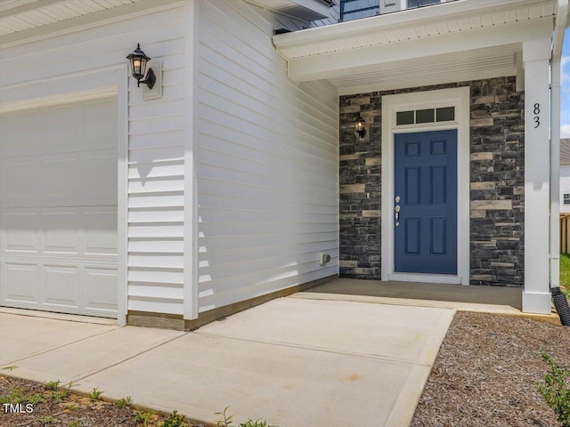 doorway to property with stone siding and an attached garage