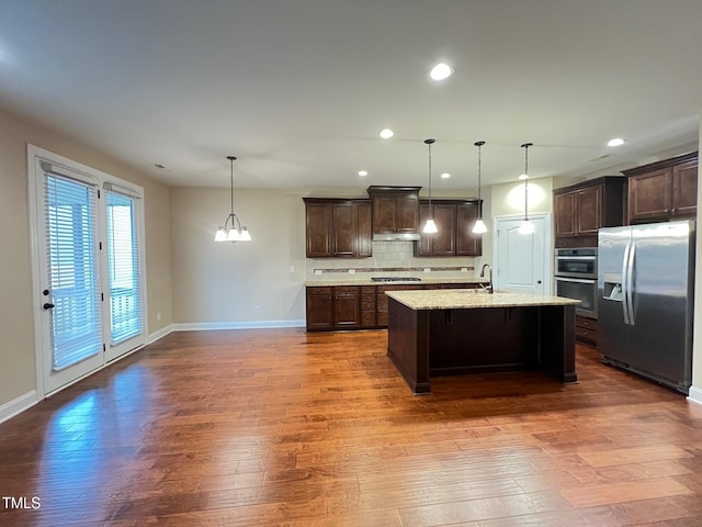 kitchen featuring pendant lighting, dark brown cabinetry, stainless steel appliances, and an island with sink