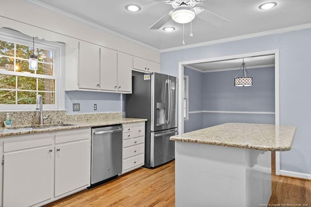 kitchen featuring appliances with stainless steel finishes, decorative light fixtures, sink, white cabinets, and crown molding