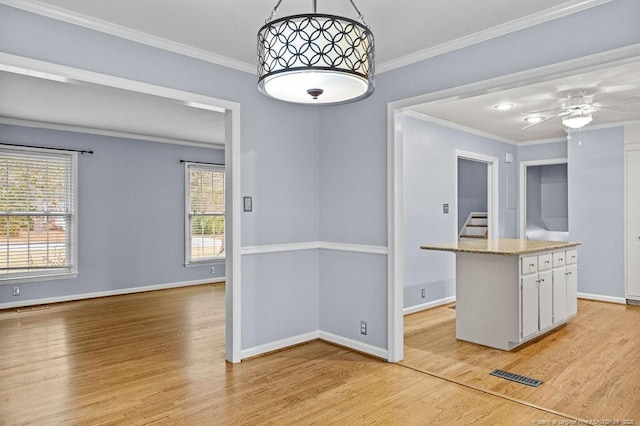 kitchen featuring ornamental molding, a kitchen island, hanging light fixtures, and light hardwood / wood-style flooring