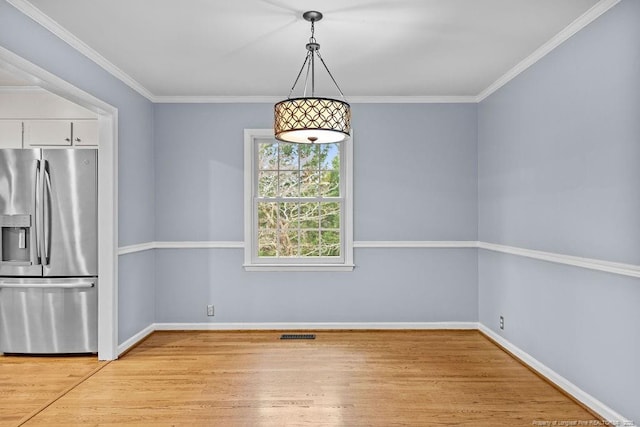 unfurnished dining area featuring crown molding and light wood-type flooring