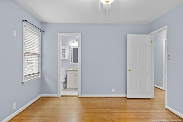 unfurnished bedroom featuring ensuite bath and light hardwood / wood-style floors