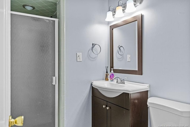 bathroom featuring a shower with door, vanity, and toilet