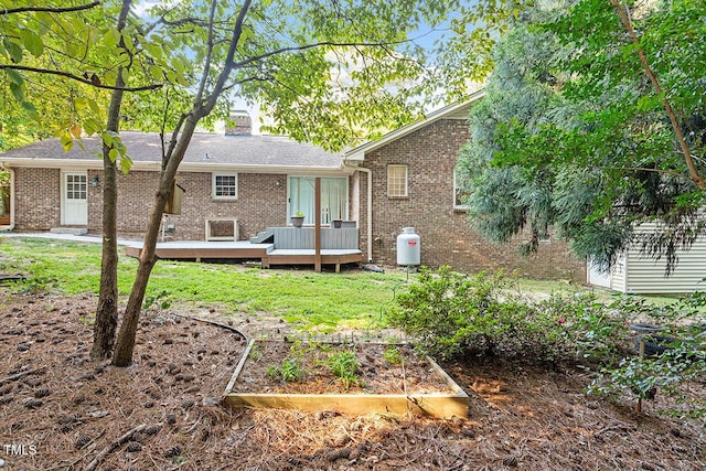 rear view of house featuring a lawn and a deck