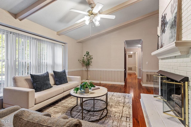 living room with vaulted ceiling with beams, a fireplace, dark hardwood / wood-style floors, and ceiling fan