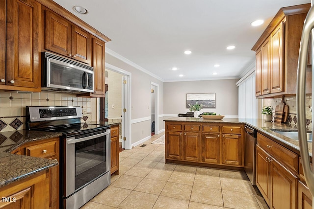 kitchen with stainless steel appliances, crown molding, kitchen peninsula, and dark stone counters