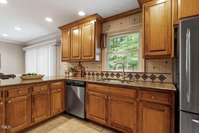 kitchen with appliances with stainless steel finishes, stone countertops, sink, and decorative backsplash