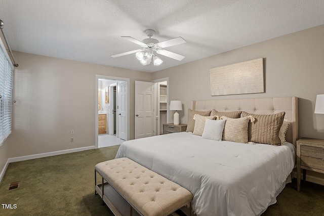 carpeted bedroom with ceiling fan, ensuite bath, a walk in closet, and a textured ceiling