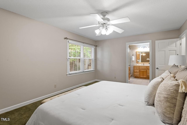 bedroom featuring light carpet, ceiling fan, ensuite bath, and a textured ceiling