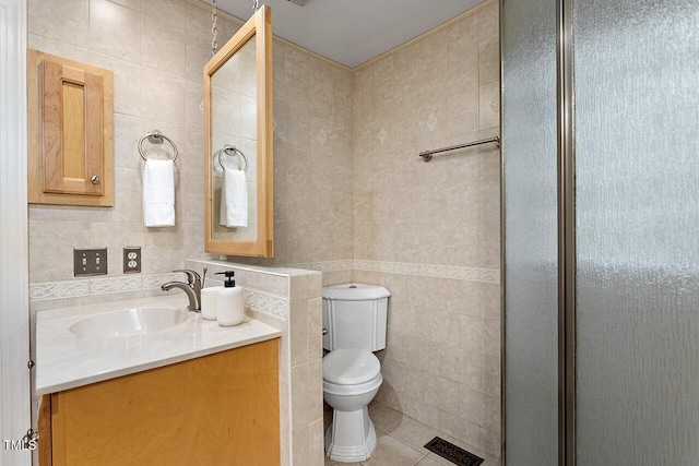 bathroom featuring toilet, a shower with shower door, tile walls, vanity, and tile patterned flooring