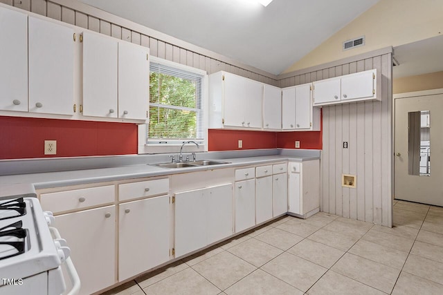 kitchen with sink, light tile patterned floors, white cabinets, vaulted ceiling, and white gas stove