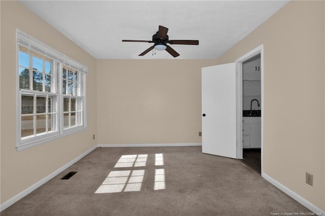 carpeted empty room featuring ceiling fan and sink