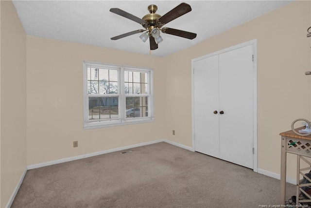 unfurnished bedroom featuring ceiling fan, light colored carpet, and a closet