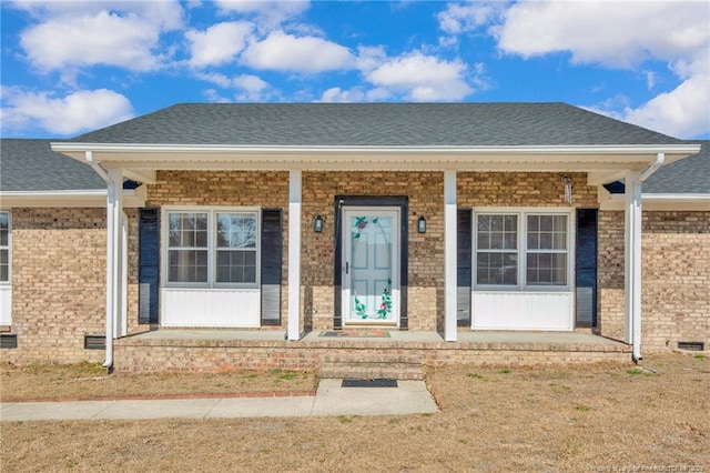 doorway to property with covered porch and a lawn