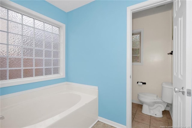 bathroom with a wealth of natural light, tile patterned floors, a tub, and toilet