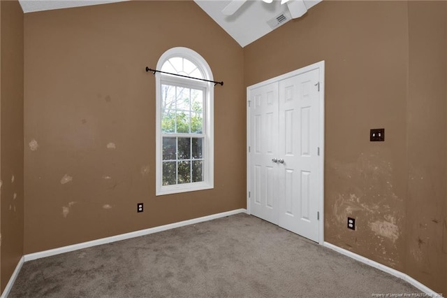 unfurnished bedroom with vaulted ceiling, light colored carpet, a closet, and ceiling fan