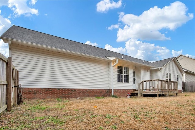 back of property with a wooden deck and a lawn